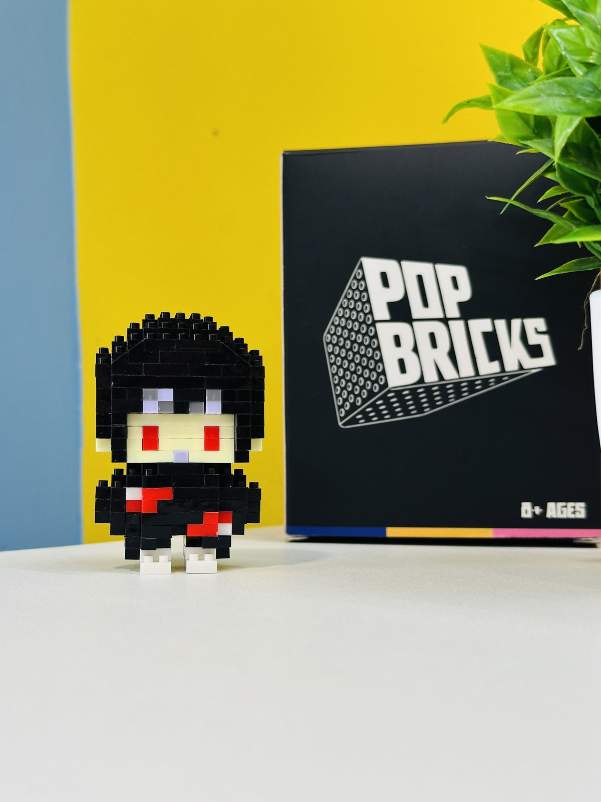 Close front view of Itachi Pop Bricks mini figure with branded packaging